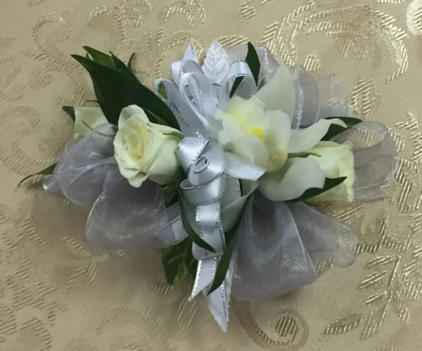 A white corsage with two roses and some leaves.