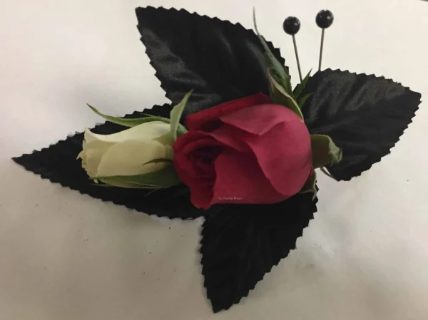 A red rose and white flower with black leaves.