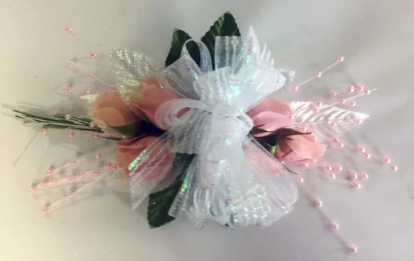 A white and pink corsage with some green leaves
