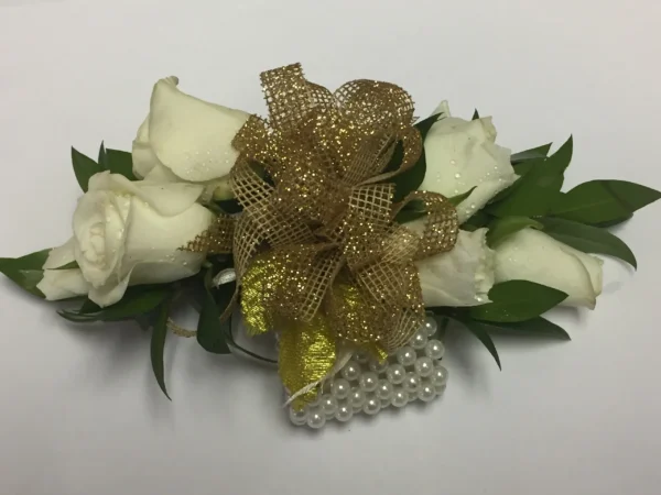 A white rose corsage with gold ribbon and pearls.