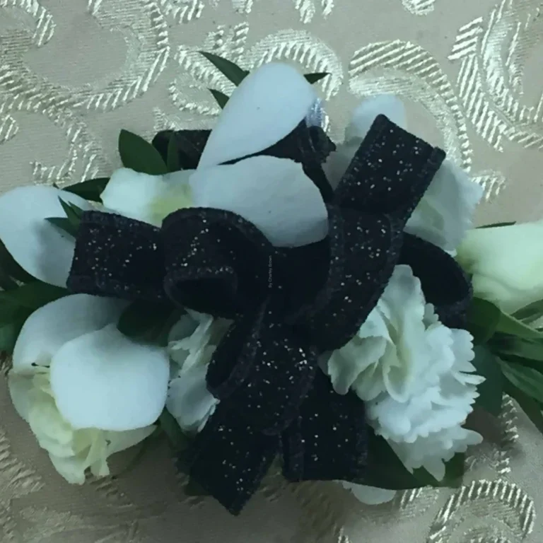 A black bow and white flowers on a table.