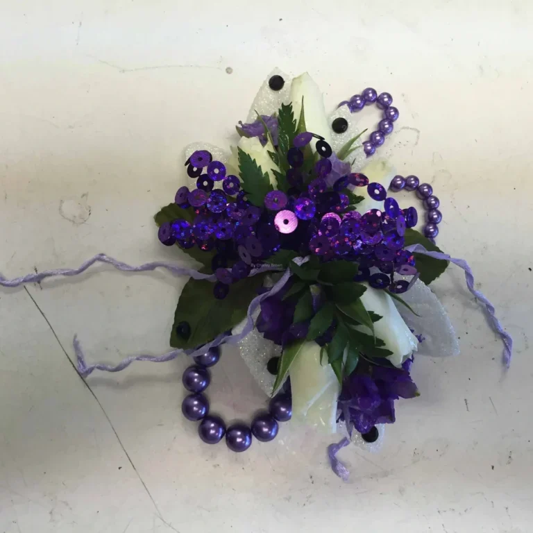 A purple flower corsage with beads and ribbons.