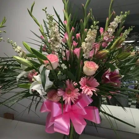 A bouquet of flowers with pink ribbon on top.