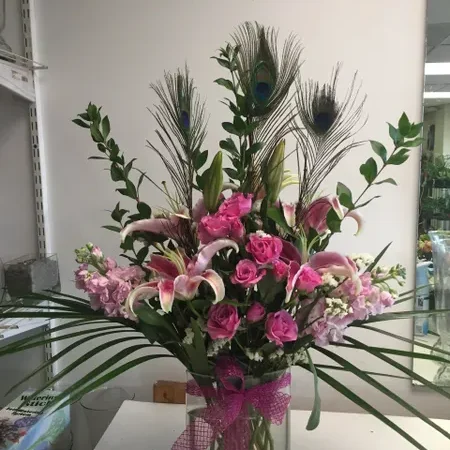A vase filled with pink flowers and peacock feathers.